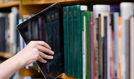 Libri su scaffale e tablet.